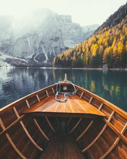 HMM – The Tourism Group Blick von einem Holzboot auf einen Bergsee mit Herbstwald und Bergen